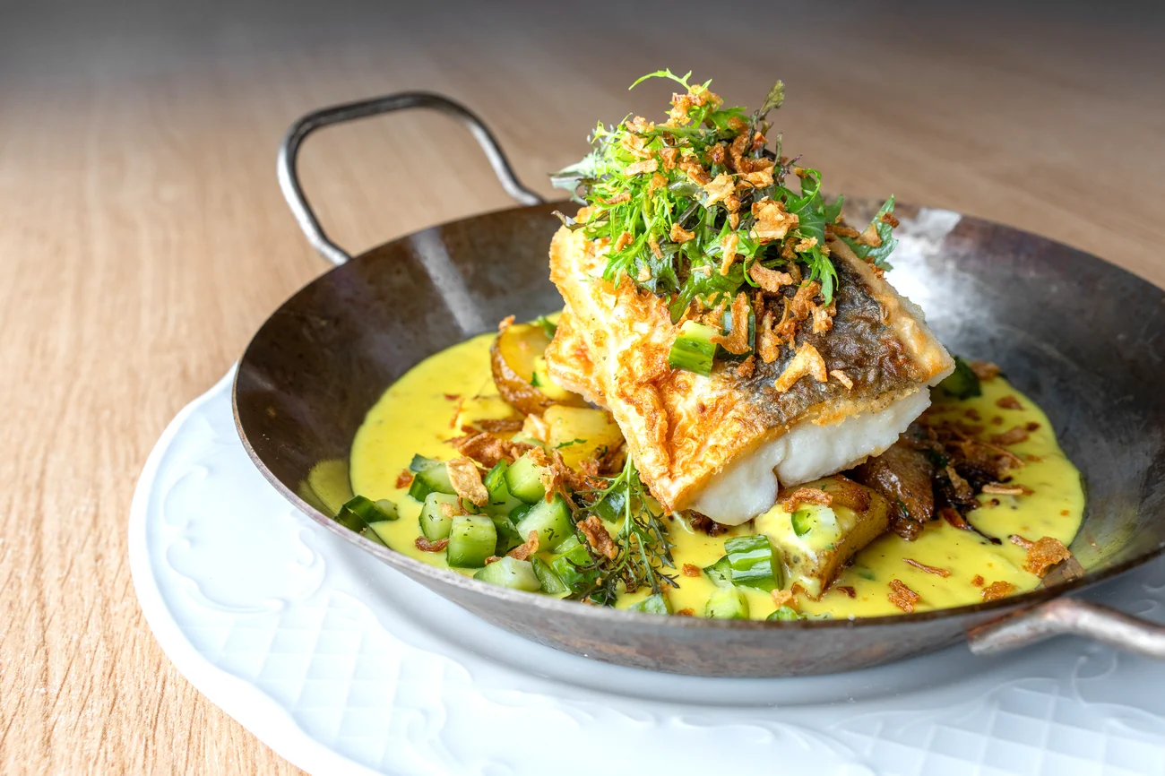 Gebratener Pannfisch mit Bratkartoffeln, garniert mit Kräutern